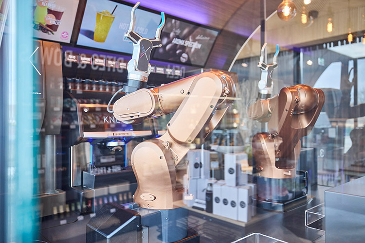 Im „Knext Future Café“ des neuen Mitarbeiterrestaurants der SAR Group bereiten drei Roboterarme in einem gläsernen Café vollautomatisiert Kaffee-Spezialitäten in Barista-Qualität zu. Hinzu kommen frisch gebrühte Tees und handgemachtes Gebäck. Foto: Wanzl / Knext