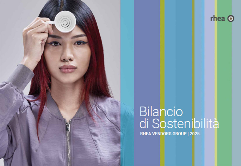 Eine Frau mit langen schwarz-roten Haaren, Nasenring und lilafarbenen Blouson hält eine Espressotasse vor ihrer Stirn. Bilancio di Sostenibilita Rhea Vendors Group 2025