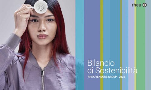 Eine Frau mit langen schwarz-roten Haaren, Nasenring und lilafarbenen Blouson hält eine Espressotasse vor ihrer Stirn. Bilancio di Sostenibilita Rhea Vendors Group 2025