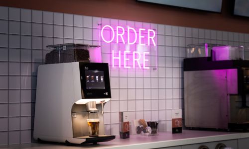 Ein Melitta-Kaffeevollautomat steht auf einer Selbstbedienungstheke.