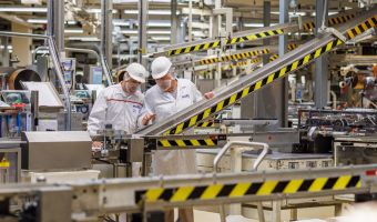 Zwei Mitarbeiter des Herstellers Mars stehen an einer Produktionsmaschine in einer Fabrik.