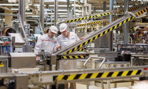 Zwei Mitarbeiter des Herstellers Mars stehen an einer Produktionsmaschine in einer Fabrik.